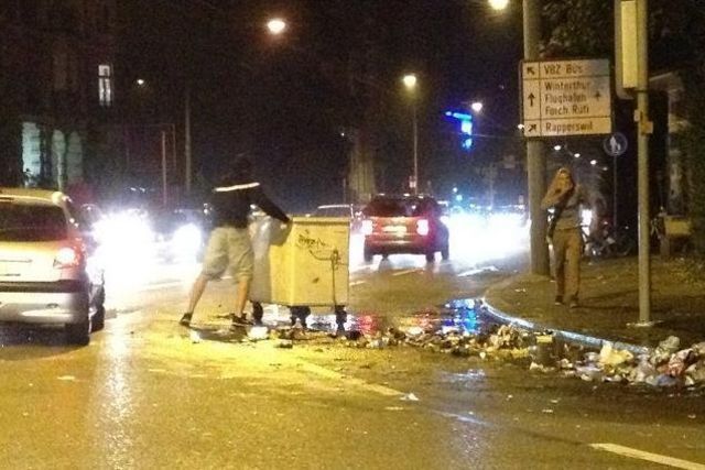 Blinde Zerstörungswut: Ein vermummter Jugendlicher blockiert den Verkehr mit Abfallcontainern.