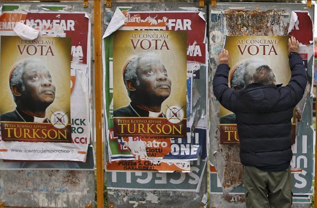 Un homme colle les affiches parodiques appelant à voter pour Peter Turkson.