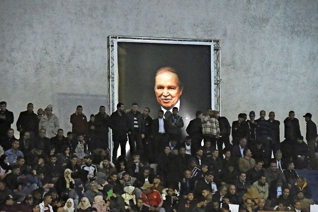  Le 9 février dernier, les partisans du Front de libération nationale (FLN) réuni dans la Coupole d’Alger désignaient Abdelaziz Bouteflika comme leur candidat à la présidentielle pour un cinquième mandat, sous un portrait géant du chef de l’État, dont les apparitions en public sont rarissimes depuis son AVC en 2013. 

(ci-dessous). Le même jour, Bouteflika a reçu Nouredine Bedoui, Ramtane Lamamra et Lakhdar Brahimi et a procédé à leurs nominations dans le cadre du processus de transition. Cela n’a pas calmé la rue algérienne, où les 5 barrés (non à un 5e mandat) ont fait place à des 4+ barrés (ci-dessus). RYAD KRAMDI/REUTERS/EPA/MOHAMED MESSARA